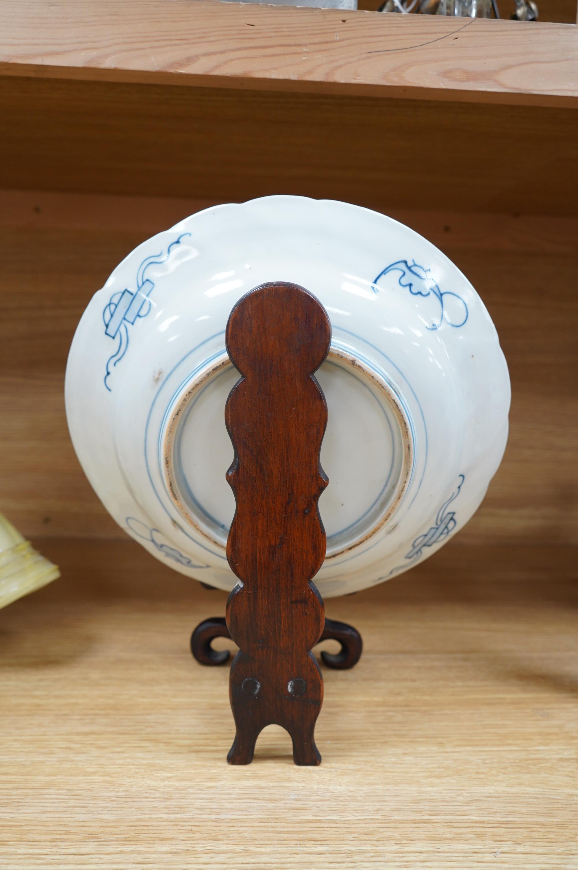 A Japanese Imari dish, circa 1900, on carved wooden stand, 31cm diameter. Condition - fine crack top right base of dish